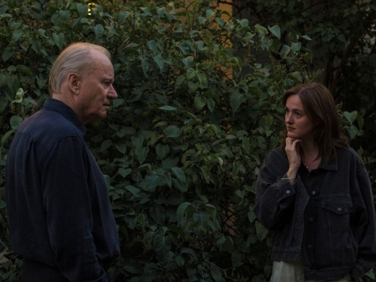 Elokuvan hahmoja ulkona puolilähikuvassa. Taustalla pensas.