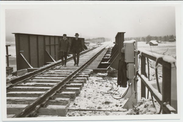 Miehet kävelevät rautatiesillan yli
