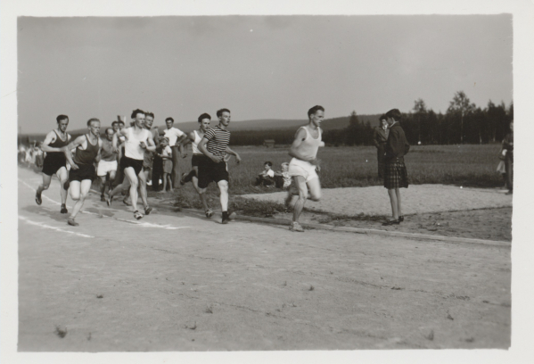 Miehet juoksemassa ponnen urheilukentällä