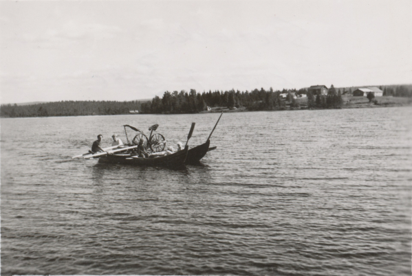 Miehet kuljettavat tavaraa kahdella veneellä