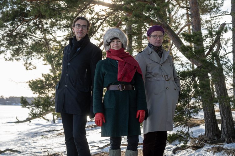 Sarastus-yhtyeen kolme jäsentä puolikuvassa talvisessa rantamaisemassa. 