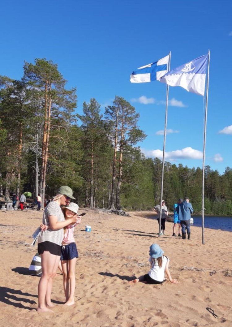 Kuva Miekojärven Orhinselänniemestä. Kuvassa on ihmisiä ja taustalla lippusaloissa Suomen ja Miekojärven veneseuran liput. 