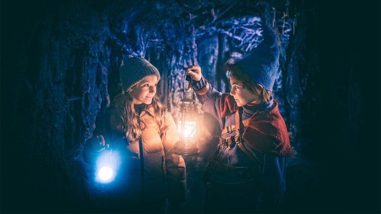 Kaksi elokuvan lapsihahmoa luolassa lyhdyt käsissään.